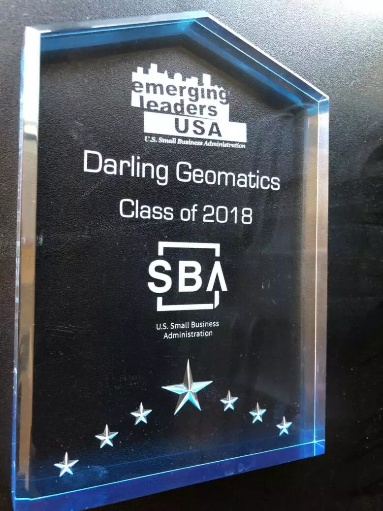 crystal trophy on a black background, the text on the plaque says "emerging leaders USA, Darling Geomatics, Class of 2018, US Small Business Administration